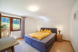 a bedroom with a bed with yellow sheets and a window at Rieglhof Apartment Hennennest in Curon Venosta
