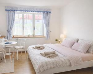a white bedroom with a large bed and a table at Ubytování Ledňáček in Lednice