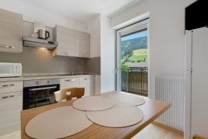 a kitchen with a wooden table and a large window at Premium App Hofer Monika in Villabassa