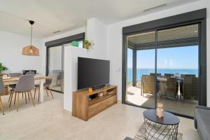 a living room with a television and a dining room at Exclusive Getaway – Ocean View in Torrox Costa