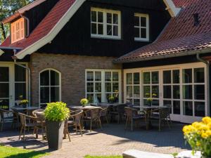 a patio with tables and chairs in front of a house at Holiday Home Het Landhuis by Interhome in Losser