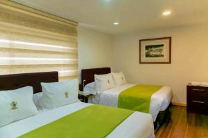 a hotel room with two beds with green and white sheets at Casa Lavim in Bogotá +20 photos