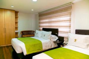 a bedroom with two beds with green and white sheets at Casa Lavim in Bogotá