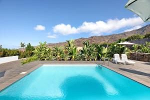 a swimming pool with two chairs and a mountain in the background at Villa Tino- Casa D in Los Llanos de Aridane