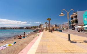 a beach with people sitting on the sand and the water at Arinaga Home in Arinaga