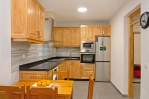 a kitchen with wooden cabinets and a table with oranges on it at Arinaga Home in Arinaga
