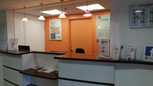 una oficina con dos escritorios de recepción y una puerta naranja en Premiere Classe Bayeux en Bayeux
