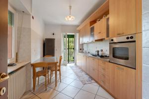 a kitchen with wooden cabinets and a table and chairs at Unique Lake View In Green Park in Nebbiuno