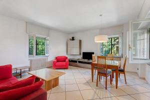 a living room with a table and a red chair at Unique Lake View In Green Park in Nebbiuno