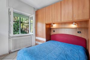 a bedroom with a blue bed and wooden cabinets at Unique Lake View In Green Park in Nebbiuno