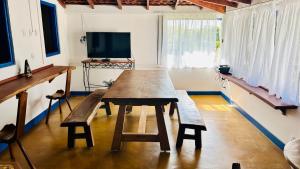 a wooden table and bench in a room with a tv at Casa da Dóta no paraíso de Furnas e Capitólio in São José da Barra