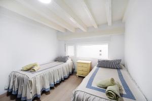two beds in a room with white walls at Piso con Encanto 2 in Cádiz