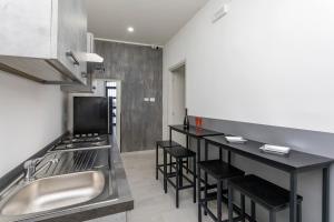a kitchen with a sink and a counter with stools at Pm House in Misterbianco