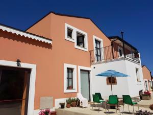 a building with a patio with chairs and an umbrella at Antico Casale Gioiosa Marea in Gioiosa Marea