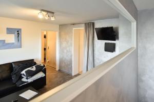 ein Wohnzimmer mit einem Sofa und einem Fernseher an der Wand in der Unterkunft Apartment Grey Stuttgart in Stuttgart