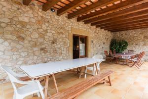 a table and chairs on a patio with a stone wall at Rural Mas Vila in Fogás de Tordera