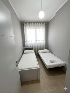a small room with two beds and a window at Radhima Beach Apartments in Vlorë +34 photos