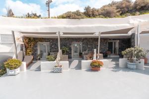 a white patio with white furniture and potted plants at Rody Caves Oia in Oia