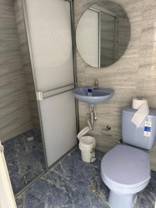 a bathroom with a toilet and a sink and a mirror at Hotel Beraka in Fortul