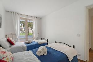 two beds in a room with a window at La Perla House in Anacapri