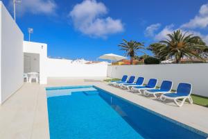 a swimming pool with blue chairs next to a building at Villa Aday and Ixeia in Cala Blanca