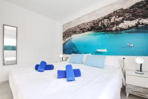 a bedroom with a large white bed with blue pillows at Villa Aday and Ixeia in Cala Blanca +20 photos