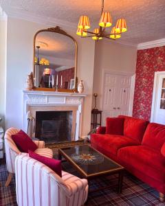 a living room with a red couch and a fireplace at Corse Lawn House Hotel in Corse