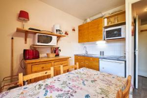 a small kitchen with a table and a microwave at 2 Alpes - appartement 2-4 pers in Les Deux Alpes +18 photos