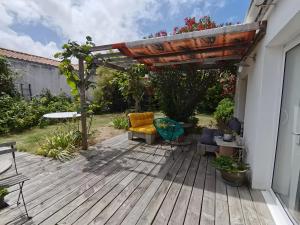 a wooden deck with a pergola and chairs on it at Maison Entre Les Ports in Les Sables-d'Olonne