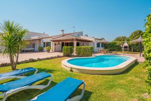a yard with two blue chairs and a swimming pool at Finca Boy in Pollença
