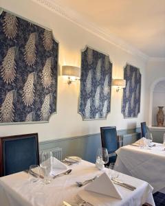 a dining room with two tables with white tablecloths at Corse Lawn House Hotel in Corse +12 photos