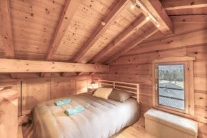 a bedroom in a log cabin with a bed and a window at Chalet cosy avec mezzanine in Verchaix