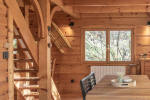 a wooden cabin with a table and a staircase at Chalet cosy avec mezzanine in Verchaix