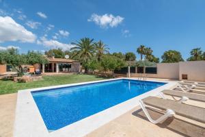 a swimming pool with two benches and a house at Capricho in Islas Baleares