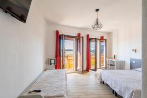 a bedroom with two beds and doors to a balcony at Affittacamere Da Riccardo in Jerzu