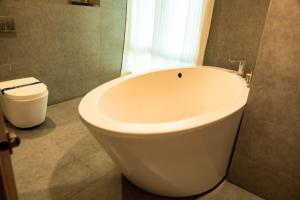 a white bath tub in a bathroom with a toilet at Banyan Palace in Chennai +24 photos