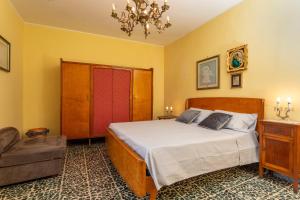 a bedroom with a bed and a chair and a chandelier at Le Logge - Bronte in Bronte