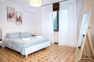 a white bedroom with a bed and a window at Luna - Apartment by the beach in Lesa