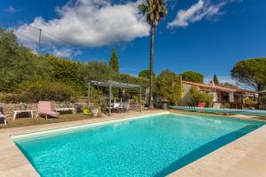 a swimming pool in front of a house with a palm tree at Gîte Les Tarentes avec piscine in Cotignac