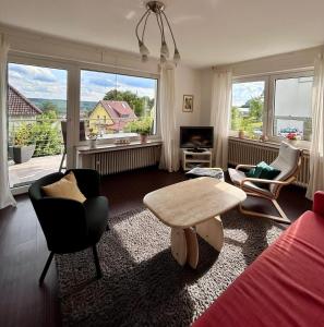 a living room with a table and chairs and windows at Ferienwohnung In den Haargärten in Möhnesee