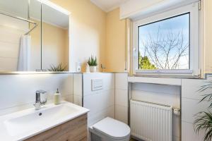 a bathroom with a sink and a toilet and a window at Ferienwohnung In den Haargärten in Möhnesee +22 photos