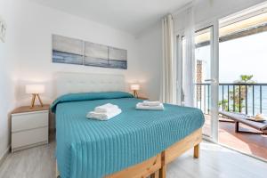a bedroom with a bed with blue sheets and a balcony at Sea Front Beach House Micaela I in Marbella +17 photos