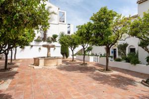 a courtyard with a fountain and trees in front of a building at Sea Front Beach House Micaela I in Marbella