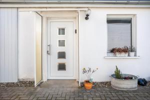 a white door on a white house with potted plants at Auszeit Nr 18 in Zempin