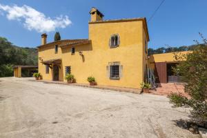 a yellow house with a dirt road in front of it at Can Marc in Dosríus