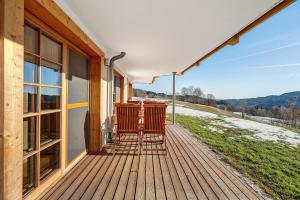 a wooden deck with two chairs on a house at Ferienwohnung Holzfäller in Lenzkirch