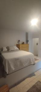 a bedroom with a white bed and a wooden dresser at Sweetcasitaarinagaplaya in Arinaga