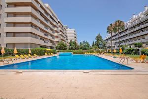 a swimming pool with chairs and umbrellas in front of a building at Marina Vilamoura Penthouse Luxury in Vilamoura