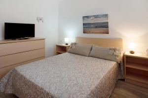 a bedroom with a bed and a flat screen tv at El Faro Sardina in Sardina