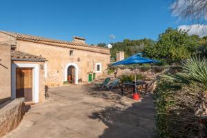 a patio with a table and a blue umbrella at Can Bonjesus in Felanitx